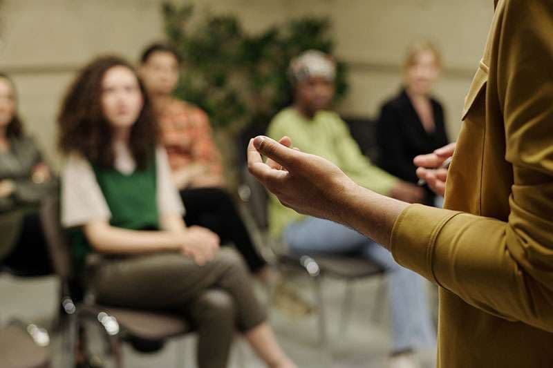 A coach speaking with a seated group during a coaching workshop