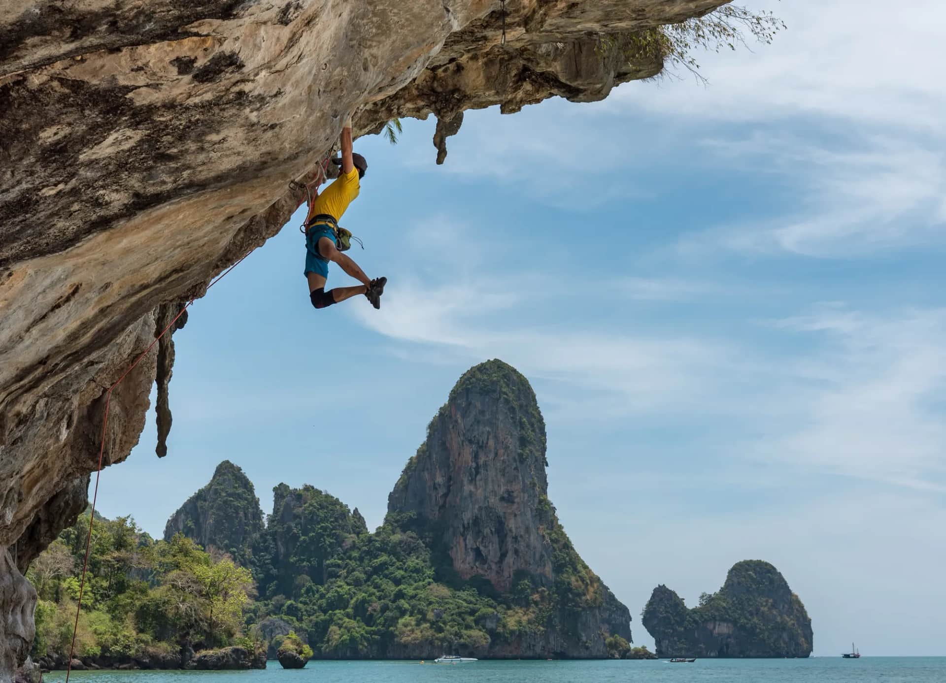 How do you measure whether capability development is actually working?. A climber hanging from a limestone overhang above a turquoise sea