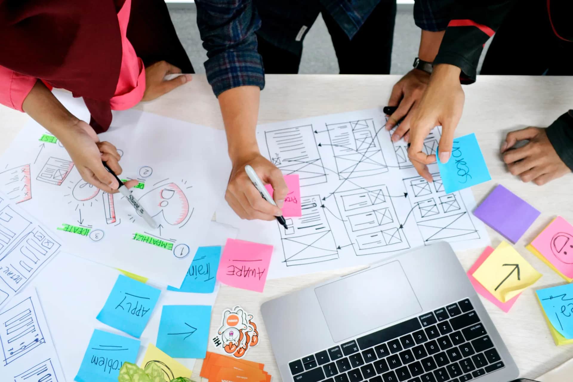 Overhead view of a team sketching page layouts among coloured sticky notes