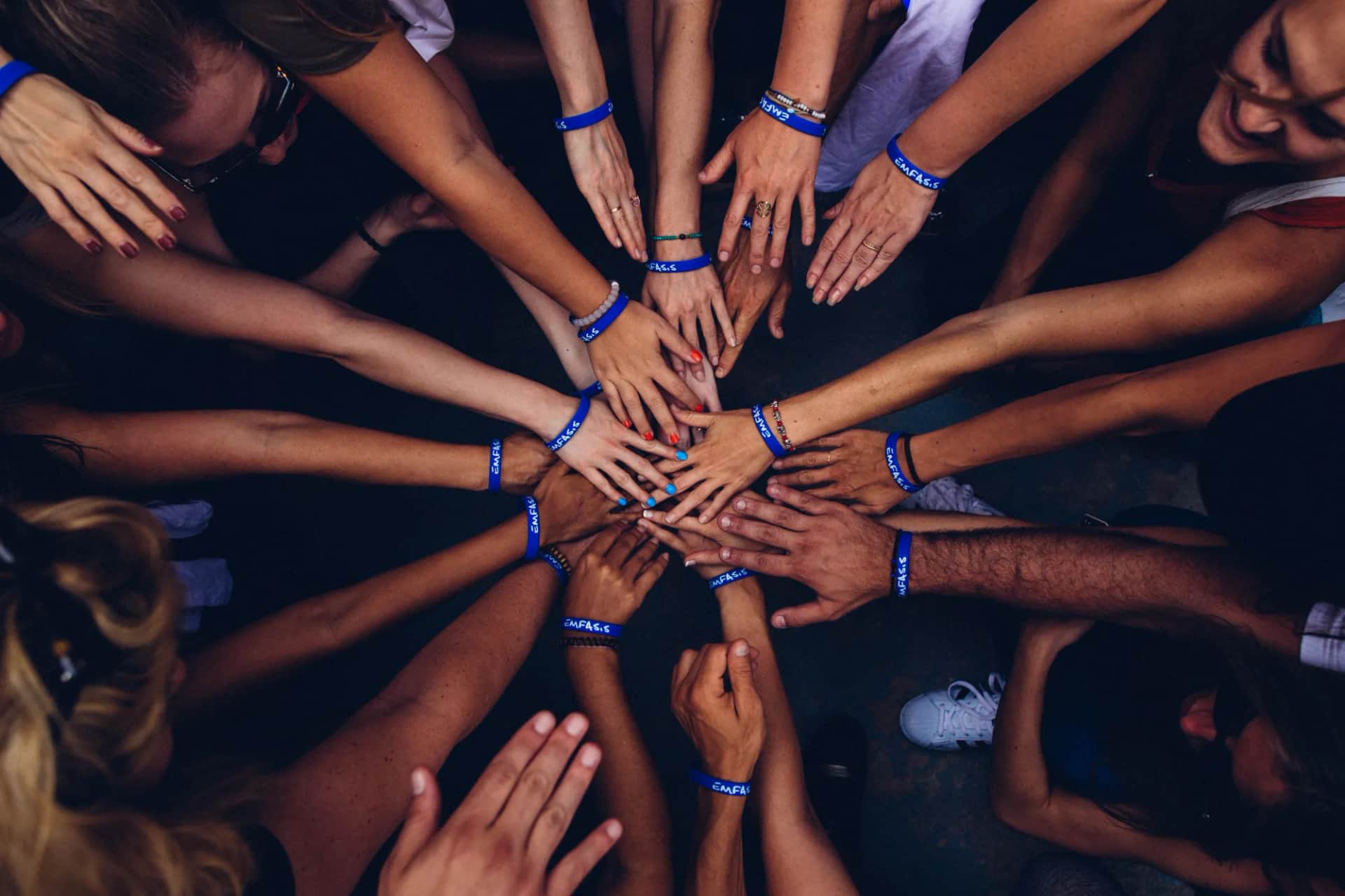 Which leadership skills still matter in the age of AI?. Overhead view of many hands reaching into a circle, wrists banded together