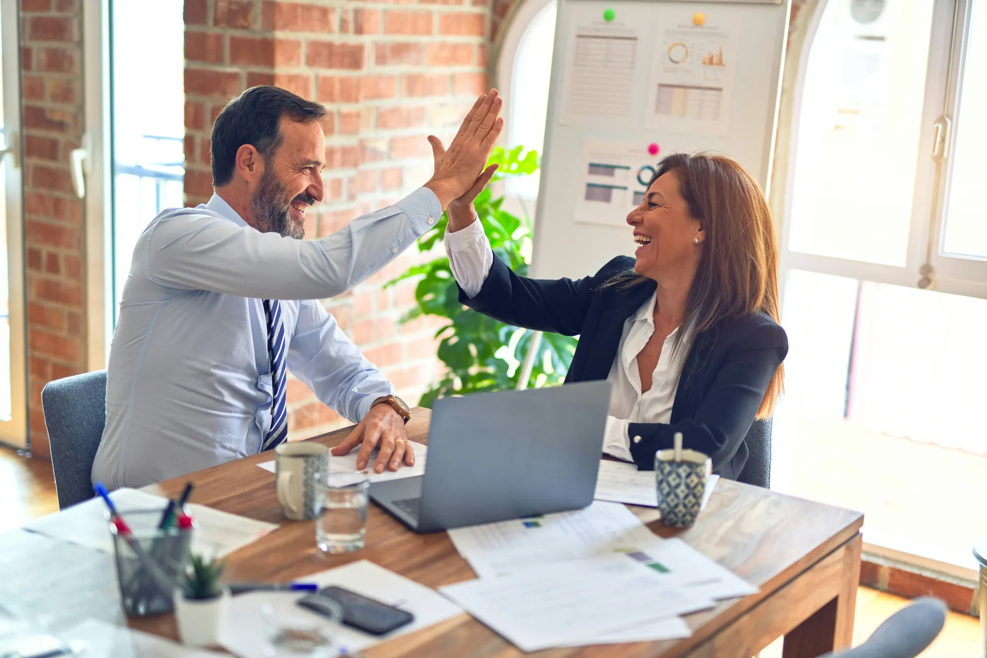 What turns line managers from accidental failure points into learning multipliers?. Two colleagues celebrate with a high five across a desk