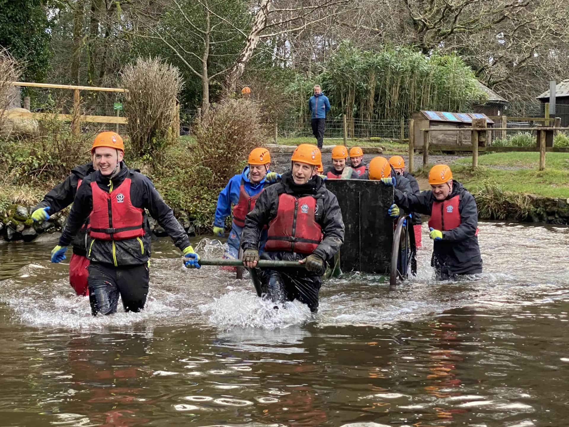 Is experiential learning still worth it in the age of AI?. A team in helmets and buoyancy aids carrying a load through a river
