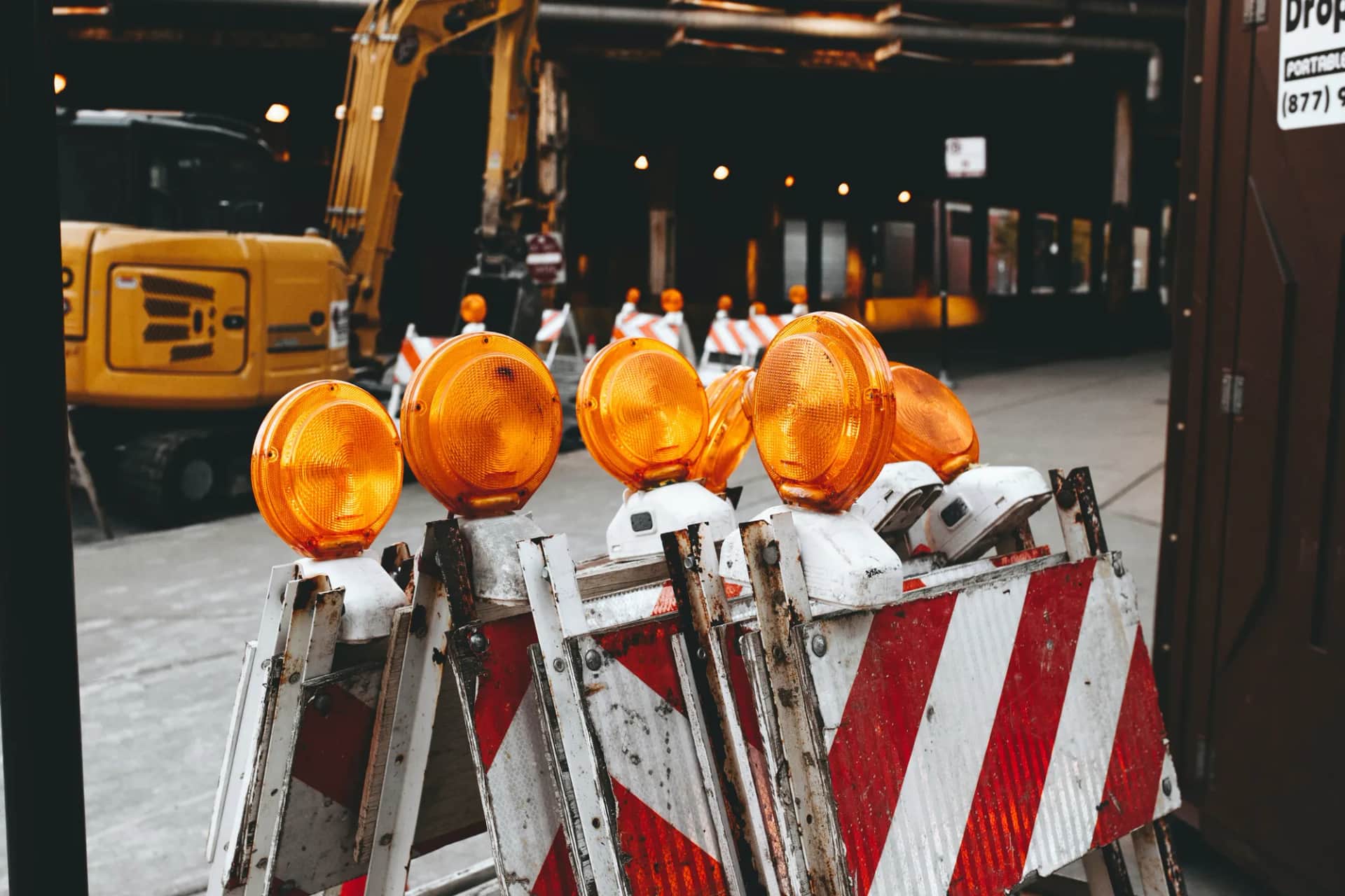 Can AI improve workplace safety without replacing human judgment?. Road barriers and amber warning lamps at a construction site