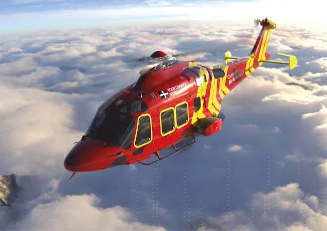 How do you build psychological safety and trust in a team where hesitation can cost a life?. An air ambulance helicopter in red and yellow livery, banking above a bank of cloud