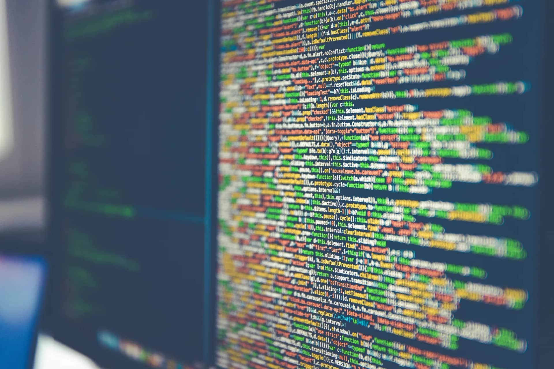 If learning isn’t a system, it doesn’t exist. A monitor filled with brightly syntax-highlighted code, the screen edge in soft focus