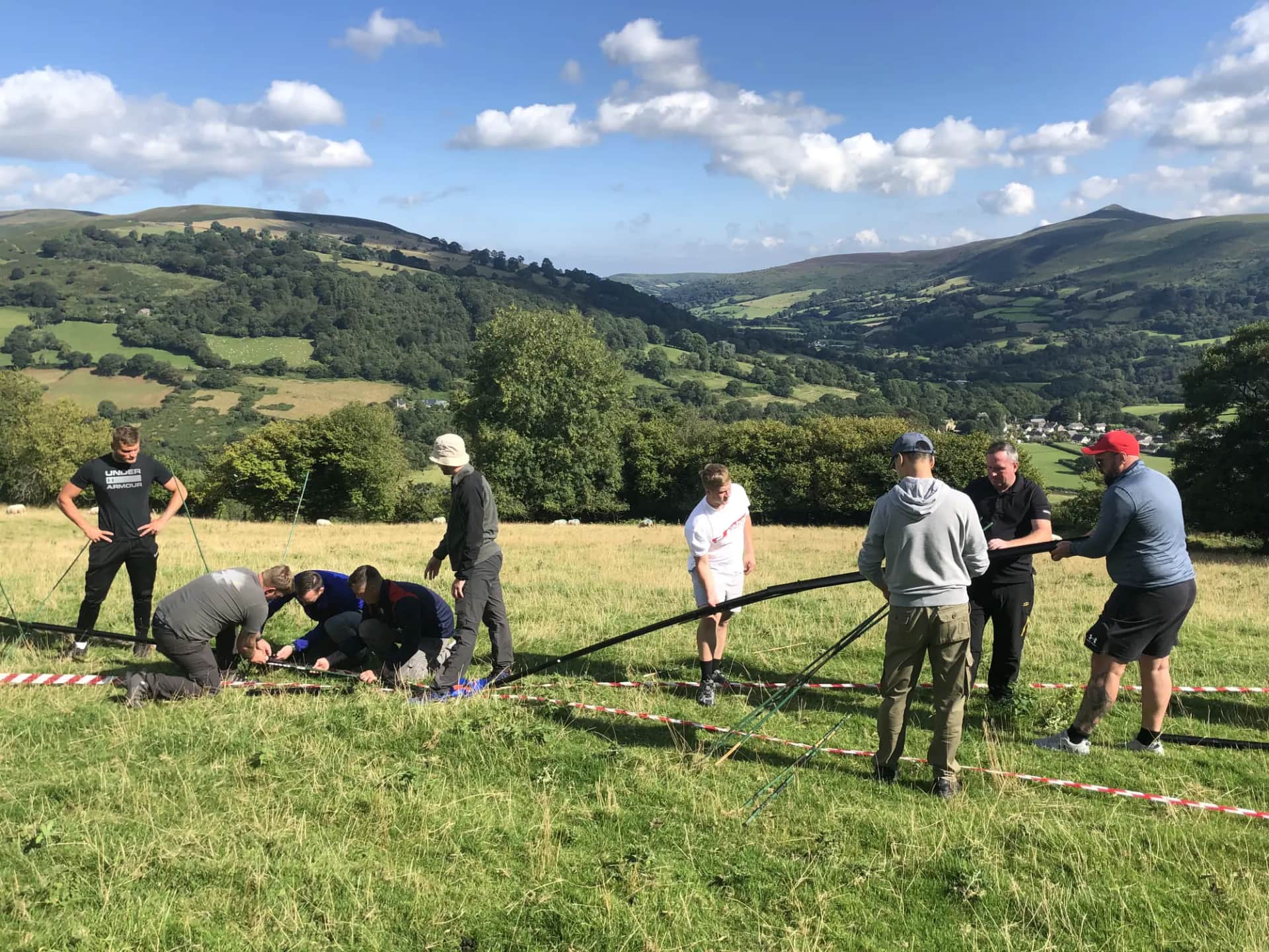 A group working through an outdoor problem-solving task on a Welsh hillside