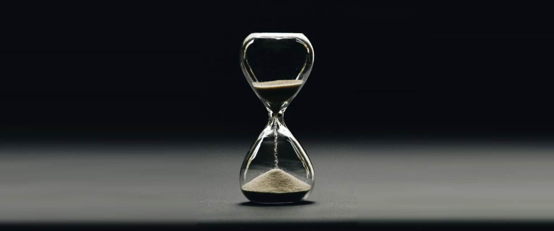 An hourglass running, its sand falling into a cone in the lower bulb