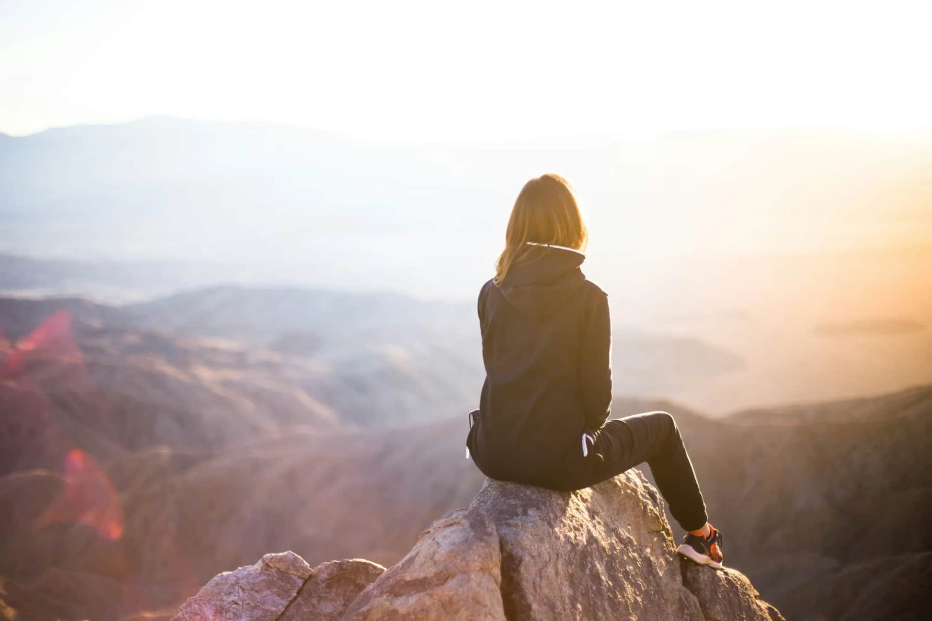 How do you give a time-pressured executive board fresh insight into its leadership?. A person sitting alone on a rocky outcrop, looking out over hills at sunrise
